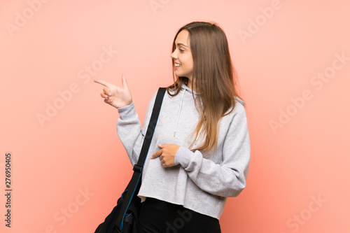 Young sport woman over isolated pink background pointing finger to the side