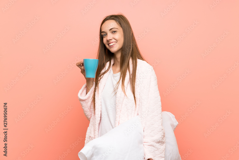 Happy Young woman in dressing gown over pink wall holding a cup of coffee Happy Young woman in dressing gown over pink wall holding a cup of coffee