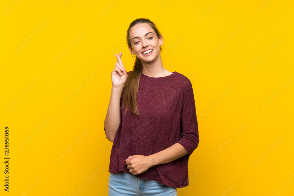 Young woman over isolated yellow background with fingers crossing and wishing the best Young woman over isolated yellow background with fingers crossing and wishing the best