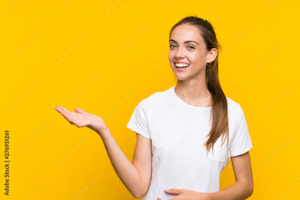 Young woman over isolated yellow background holding copyspace imaginary on the palm Young woman over isolated yellow background holding copyspace imaginary on the palm