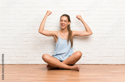Young woman sitting on the floor celebrating a victory