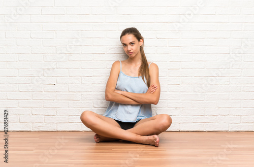 Young woman sitting on the floor keeping arms crossed