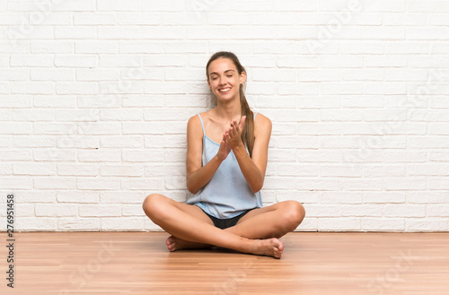 Young woman sitting on the floor applauding