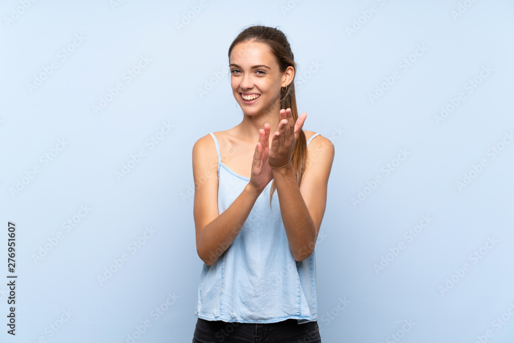 Young woman over isolated blue background applauding after presentation in a conference Young woman over isolated blue background applauding after presentation in a conference