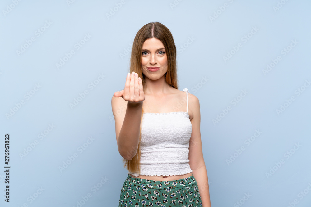Young woman over isolated blue background inviting to come with hand. Happy that you came Young woman over isolated blue background inviting to come with hand. Happy that you came