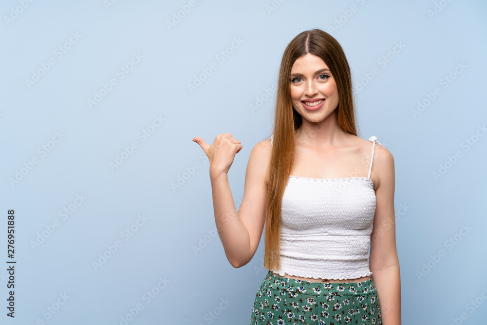 Young woman over isolated blue background pointing to the side to present a product Young woman over isolated blue background pointing to the side to present a product