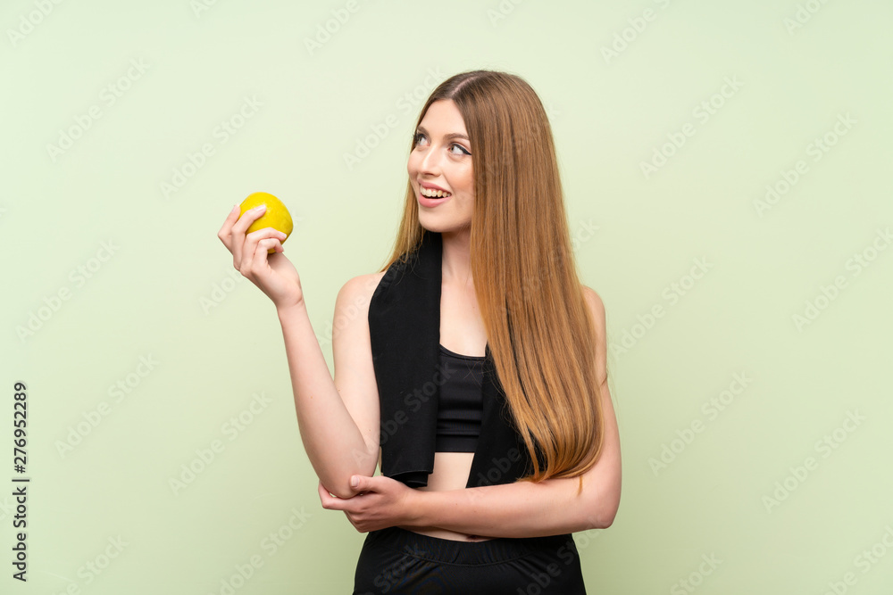 Young sport woman over isolated green background with an apple Young sport woman over isolated green background with an apple
