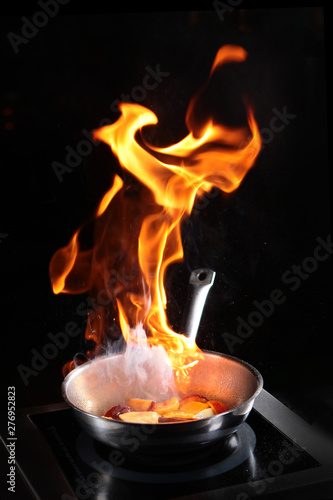 Flame over the pan when cooking flambe fruit. Food show for restaurant visitors. The concept of high cuisine. Photos in the interior.