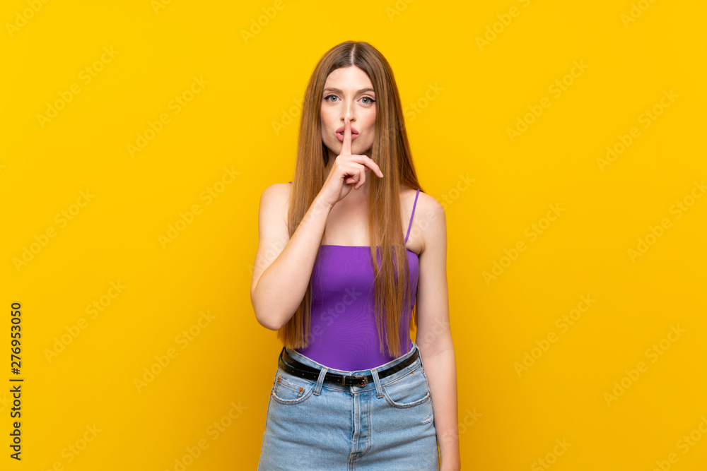 Young woman over isolated yellow background showing a sign of silence gesture putting finger in mouth Young woman over isolated yellow background showing a sign of silence gesture putting finger in mouth