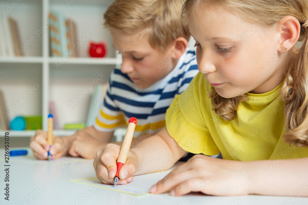 Cute schoolchildren are came back to school and learning at the table in classroom Cute schoolchildren are came back to school and learning at the table in classroom