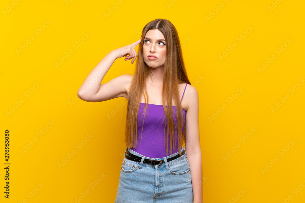 Young woman over isolated yellow background making the gesture of madness putting finger on the head