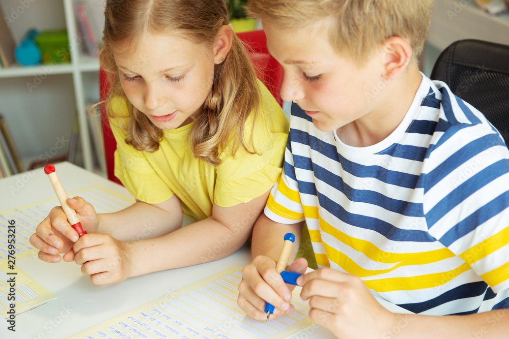 Cute clever schoolchildren are came back to school and studying together at the table in classroom Cute clever schoolchildren are came back to school and studying together at the table in classroom