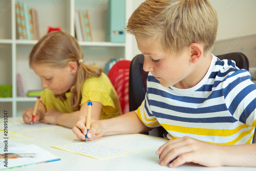 Cute schoolchildren are came back to school and learning at the table in classroom Cute schoolchildren are came back to school and learning at the table in classroom