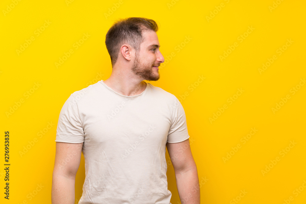 Handsome man over yellow background looking to the side Handsome man over yellow background looking to the side