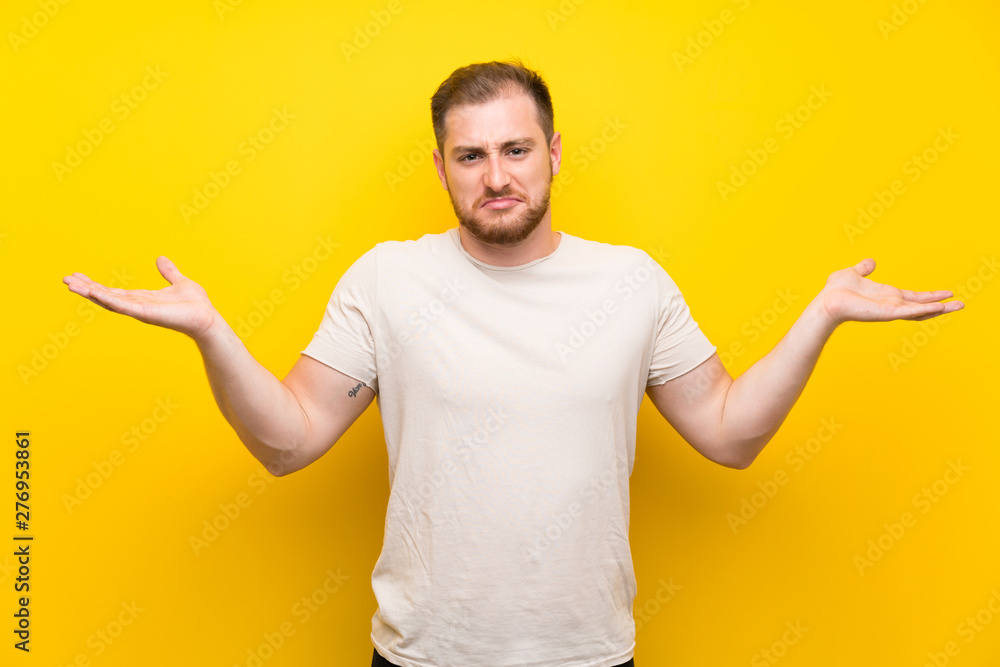 Handsome man over yellow background having doubts with confuse face expression Handsome man over yellow background having doubts with confuse face expression
