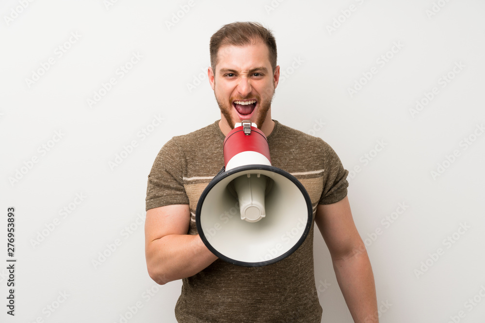 Handsome man over isolated white wall shouting through a megaphone Handsome man over isolated white wall shouting through a megaphone