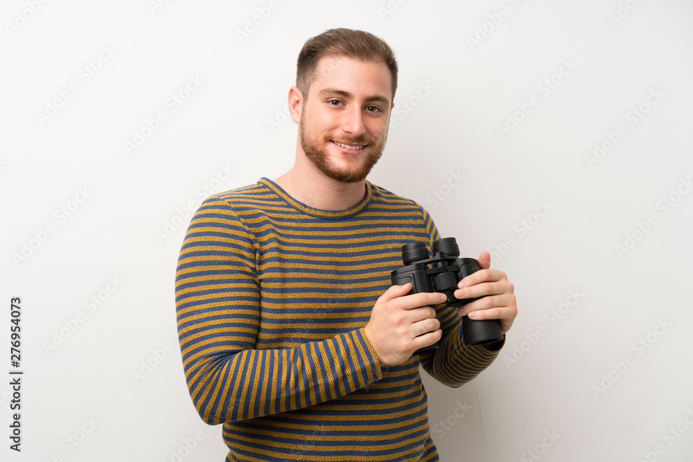 Handsome man over isolated white wall with black binoculars Handsome man over isolated white wall with black binoculars
