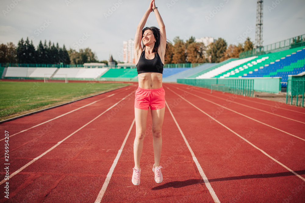 Attractive sporty brunette womang girl doing workout with jump rope in sun rays at the stadium