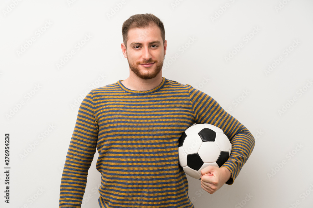 Handsome man over isolated white wall holding a soccer ball