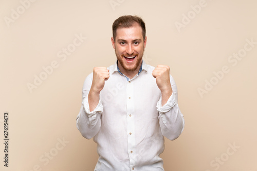 Blonde man over isolated background celebrating a victory in winner position