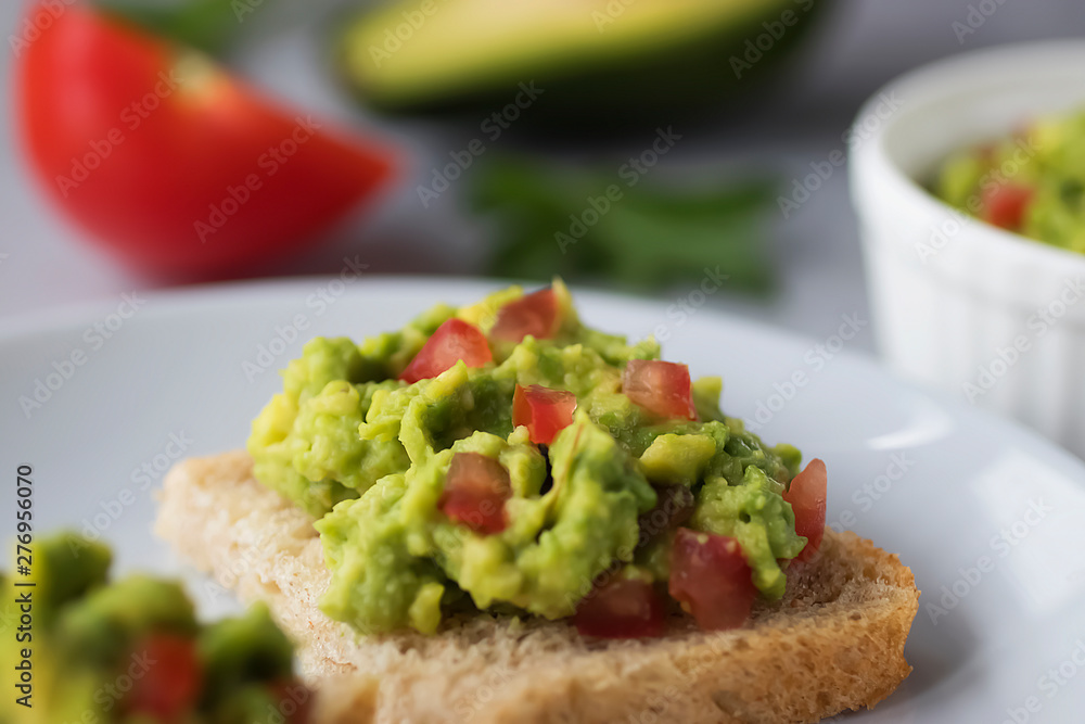 Toasts with an avocado snack and fresh vegetables on a gray background. Toasts with an avocado snack and fresh vegetables on a gray background.