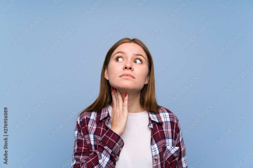 Young woman over blue wall standing and thinking an idea Young woman over blue wall standing and thinking an idea
