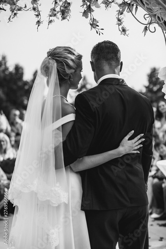 A bride and a groom are hugging in front of the guests. Black and white picture.
