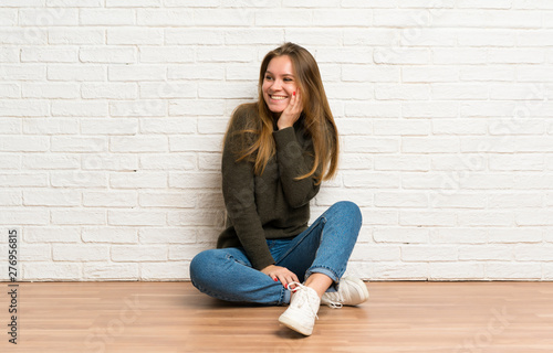 Young woman sitting on the floor smiling a lot © luismolinero