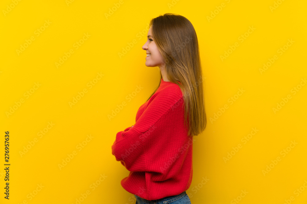 Young woman over yellow wall in lateral position Young woman over yellow wall in lateral position