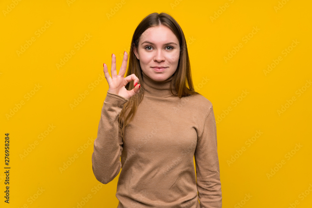 Young woman over colorful background showing an ok sign with fingers Young woman over colorful background showing an ok sign with fingers