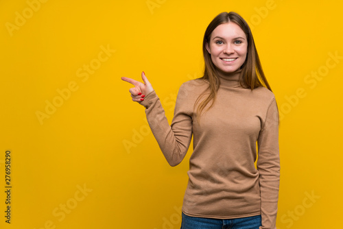 Young woman over colorful background pointing finger to the side
