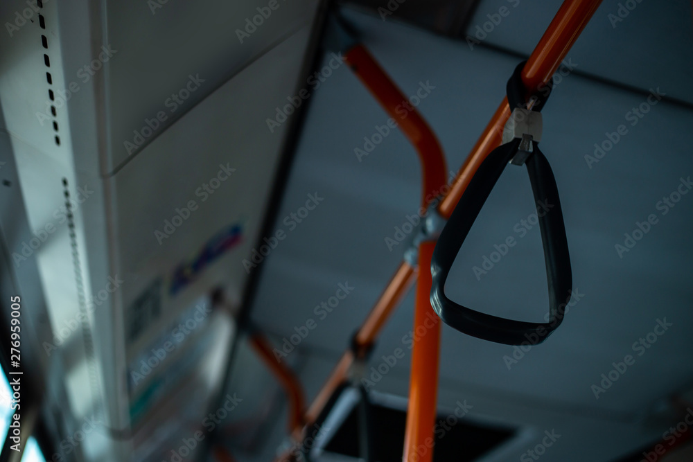 Plastic grip handles on bars in bus interior – Orange metallic hand rails in the public transport – Comfortable and practical mean of travel in the city