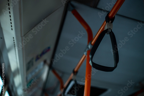 Plastic grip handles on bars in bus interior – Orange metallic hand rails in the public transport – Comfortable and practical mean of travel in the city