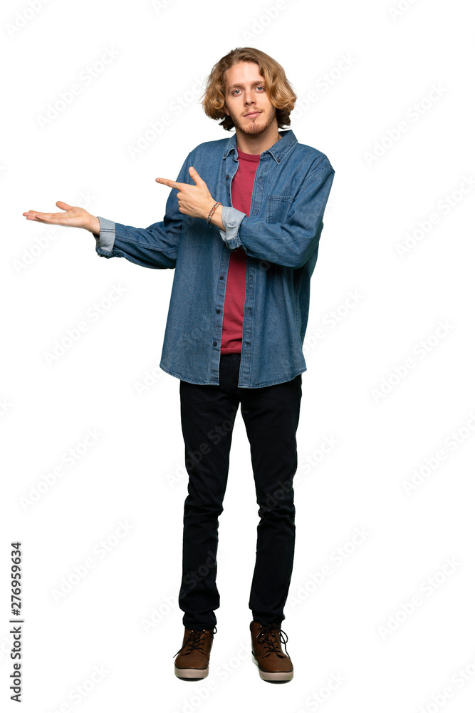 Full-length shot of Blonde man holding copyspace imaginary on the palm to insert an ad over isolated white background Full-length shot of Blonde man holding copyspace imaginary on the palm to insert an ad over isolated white background