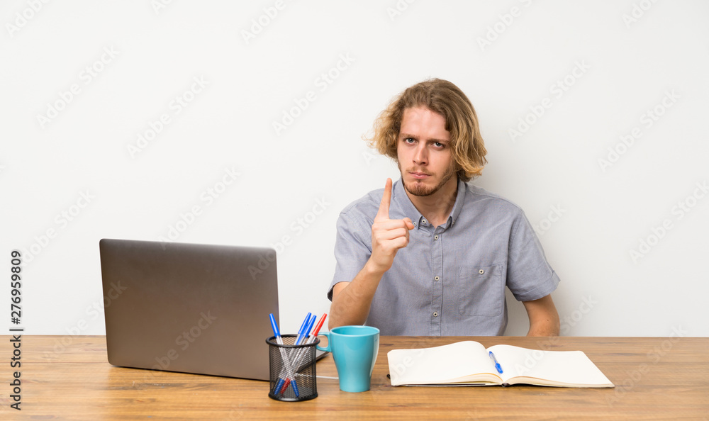 Blonde man with a laptop frustrated and pointing to the front Blonde man with a laptop frustrated and pointing to the front