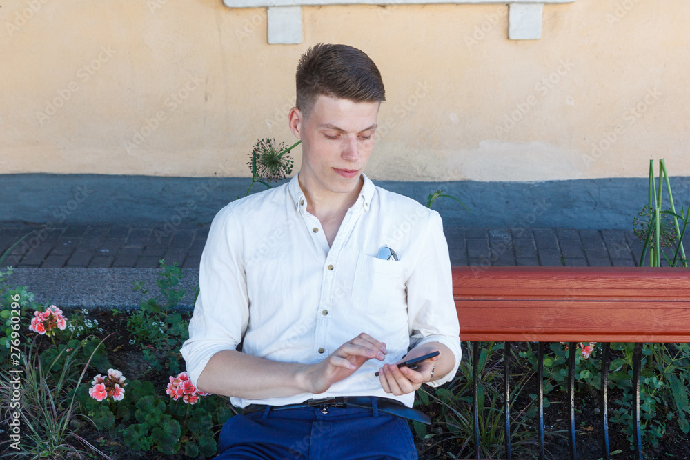 Φωτογραφία Outdoor portrait of modern young man with mobile phone in the bench
