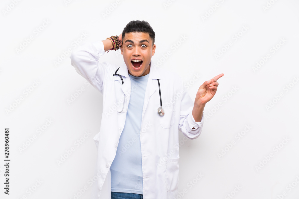 Young doctor man over isolated white wall surprised and pointing finger to the side Young doctor man over isolated white wall surprised and pointing finger to the side
