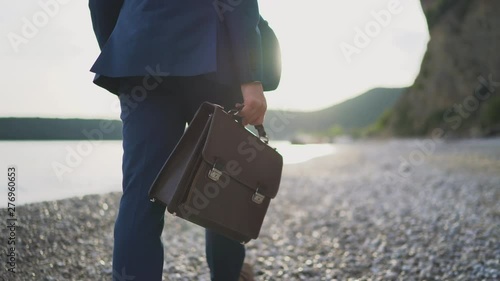 A man in a business suit is walking along the beach towards the sea photo