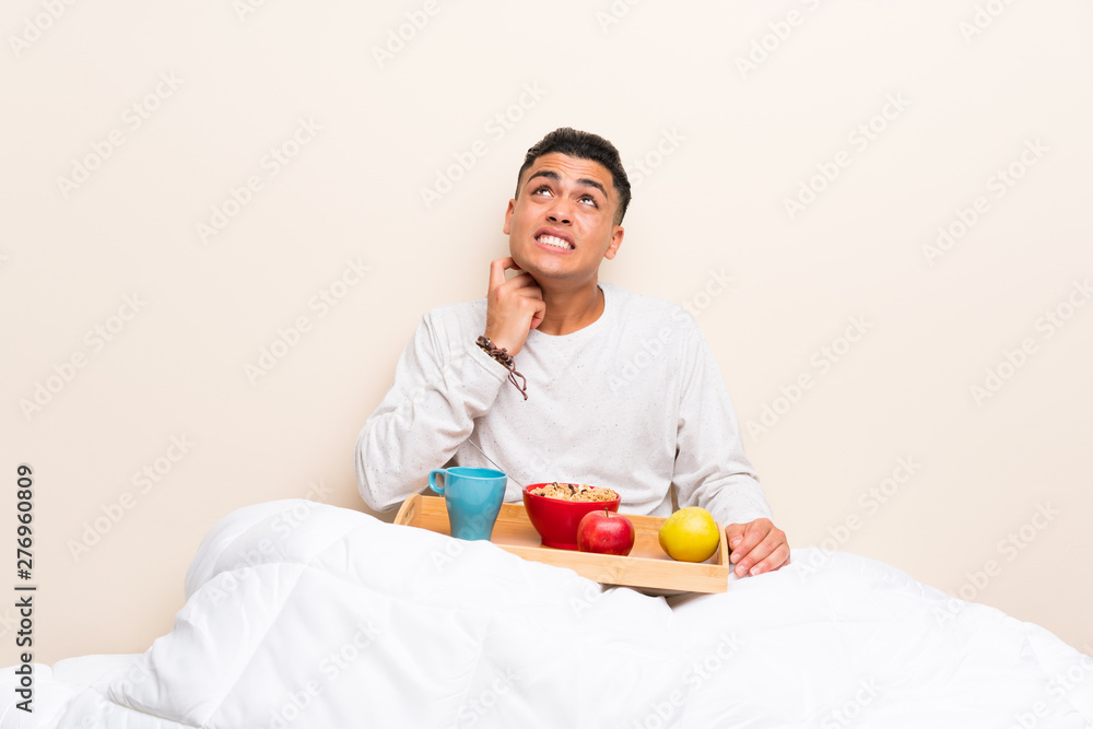 Young man having breakfast in bed thinking an idea Young man having breakfast in bed thinking an idea