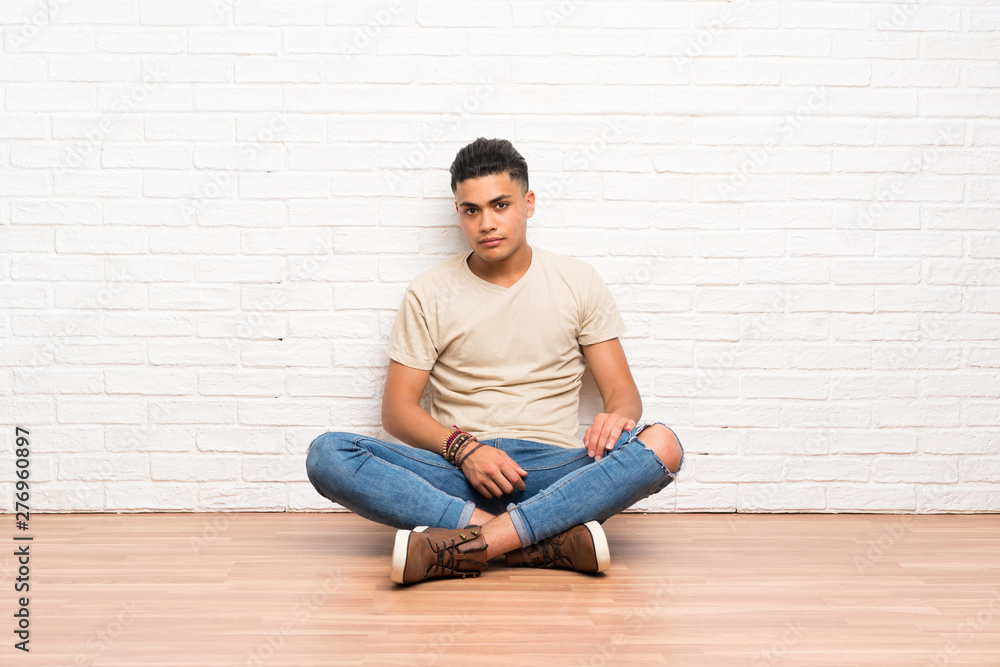 Young man sitting on the floor keeping arms crossed
