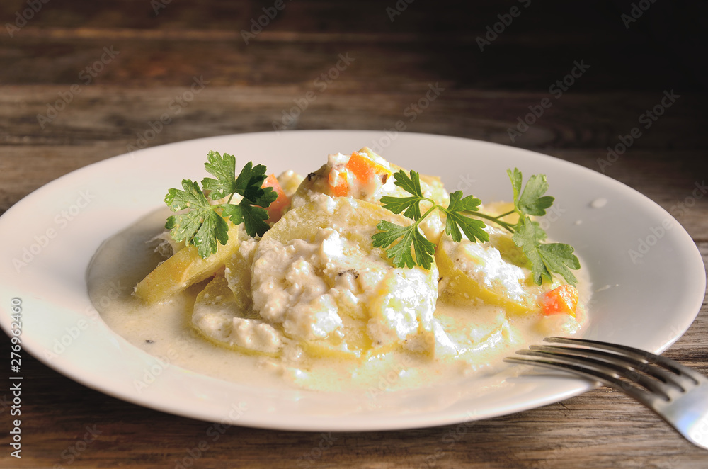 Courgettes in garlic sauce in a white plate on a wooden table. Courgettes in garlic sauce in a white plate on a wooden table.
