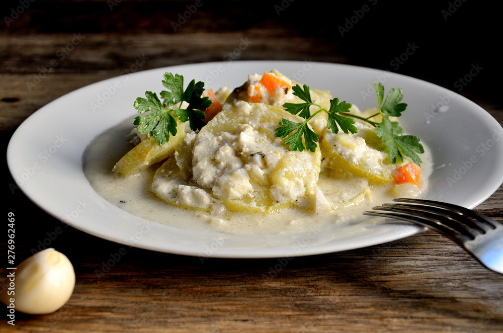 Courgettes in garlic sauce, in a white plate on a wooden table. Courgettes in garlic sauce, in a white plate on a wooden table.