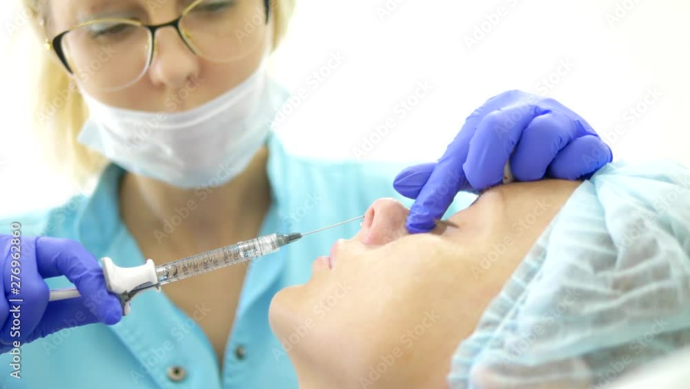 Cosmetology concept. Nose contour correction. Doctor cosmetologist injects a filler into the nose of the patient's woman. close-up Cosmetology concept. Nose contour correction. Doctor cosmetologist injects a filler into the nose of the patient's woman. close-up