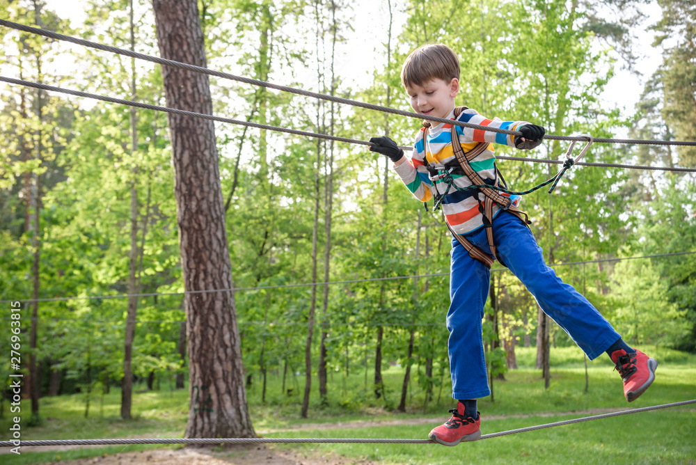 Fototapeta premium Cute child boy playing. Artworks depict games at eco resort which includes flying fox or spider net. Every childhood matters. Toddler age. Children fun