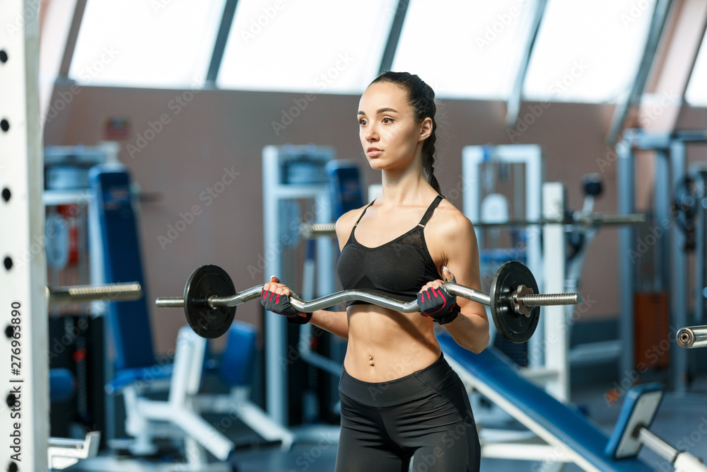 Woman in a gym perfoms exercises with a barbell Woman in a gym perfoms exercises with a barbell