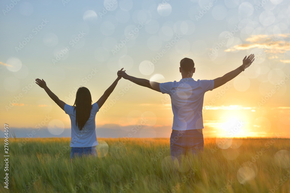 Young couple feeling free in a beautiful natural setting, in what field at sunset Young couple feeling free in a beautiful natural setting, in what field at sunset