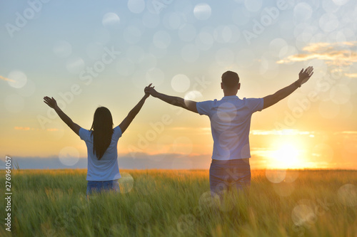 Young couple feeling free in a beautiful natural setting, in what field at sunset