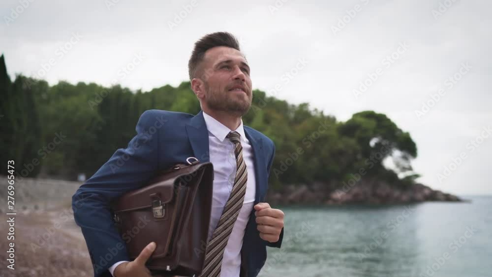 Successful Businessman with Briefcase is Running along the Beach at Sea background 4K Successful Businessman with Briefcase is Running along the Beach at Sea background 4K
