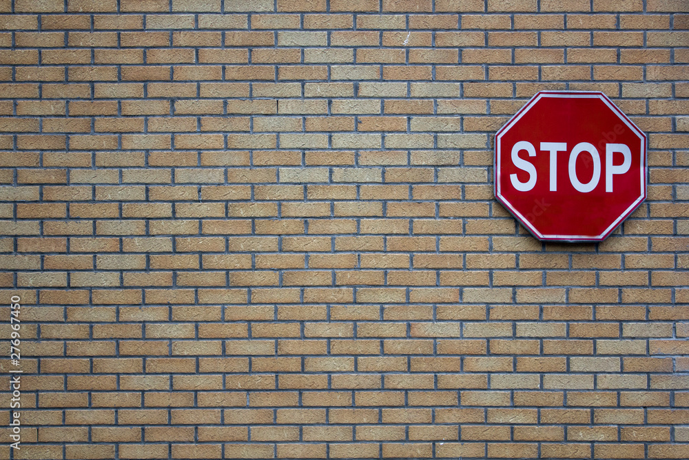 brick wall of gray and yellow bricks with a red road stop sign. rough surface texture brick wall of gray and yellow bricks with a red road stop sign. rough surface texture