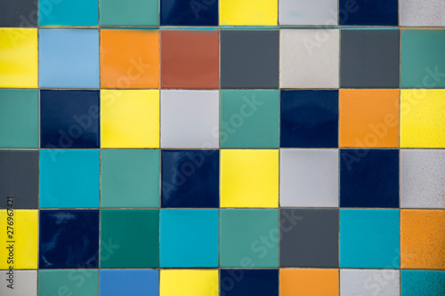 wall of bright multi-colored yellow, blue, white, gray square ceramic tiles. rough surface texture © Pavel